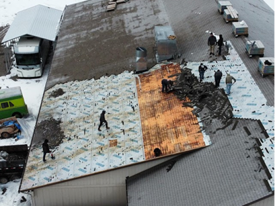 Aerial view of workers fixing snow-covered roof of a building