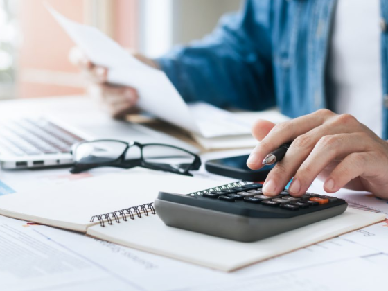 Calculating finances with papers and a laptop on the desk.