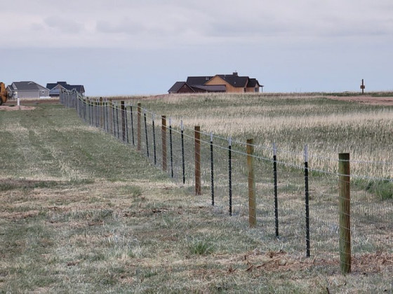 Rural landscape with a wire fence and houses in the distance