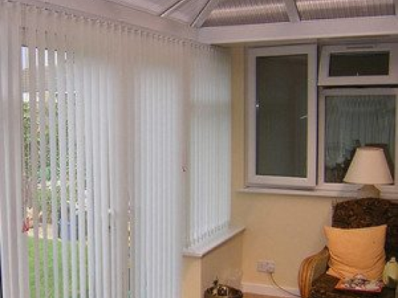 Bright conservatory featuring white blinds and an armchair