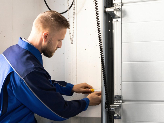 Man in blue uniform fixing garage door mechanism