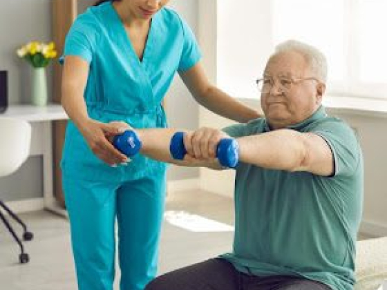 Senior exercising with support from a caretaker in a bright room