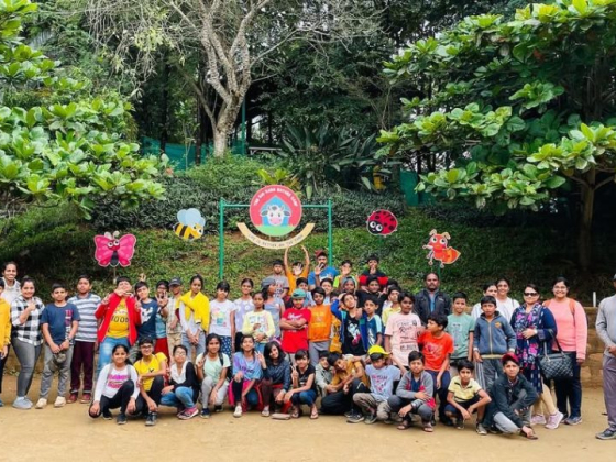 Children and adults standing together under trees