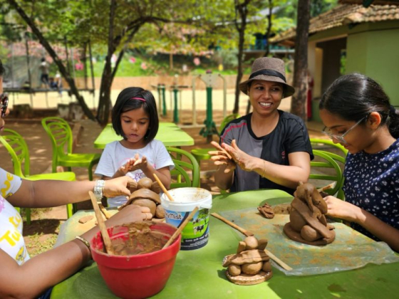 Group sculpting clay art at an outdoor table