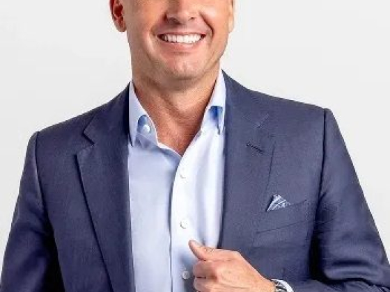 Bald man in blue suit smiling confidently