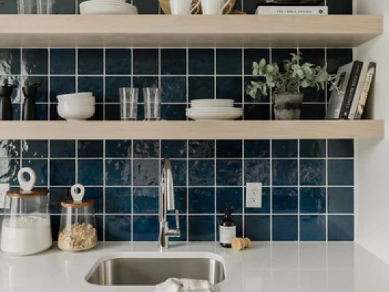 Stylish kitchen sink area with shelves and dark tiles