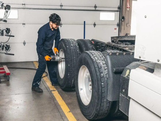 Man using a tool on truck tires in a workshop
