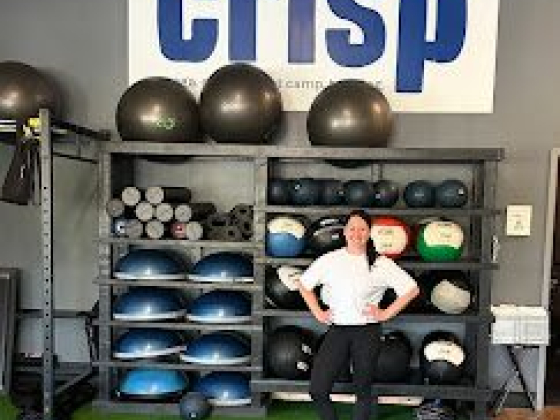 Smiling woman poses near gym gear and 'crisp' sign