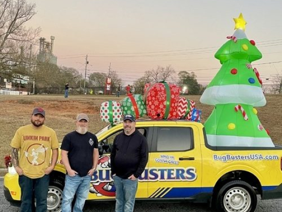 Men standing beside a holiday-themed Bug Busters truck