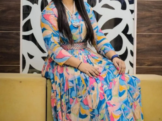 Woman wearing bright floral dress, sitting on a sofa
