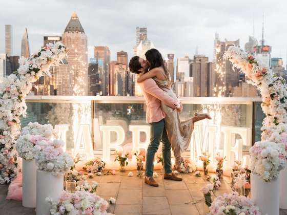 Marriage proposal with flowers and city skyline backdrop