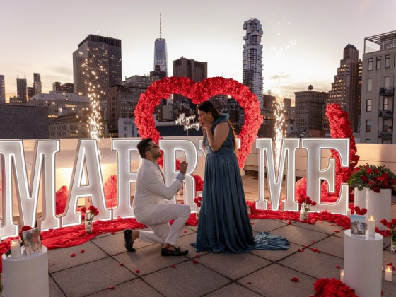 Man proposes with 'Marry Me' sign and rose petals