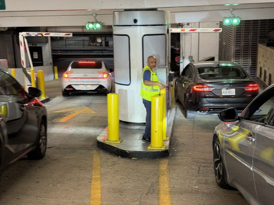 Cars waiting at a parking garage exit with an attendant present