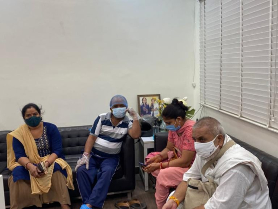 Group with face masks seated on couches indoors