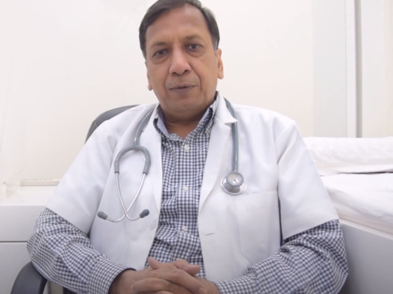 A doctor in white coat seated in a medical office