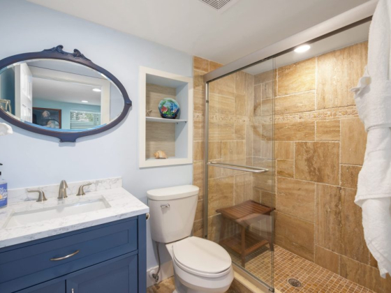 Bathroom featuring blue vanity, mirror, and tiled shower