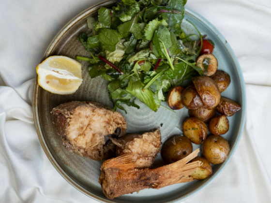 A meal with fish, salad, and roasted potatoes on a plate