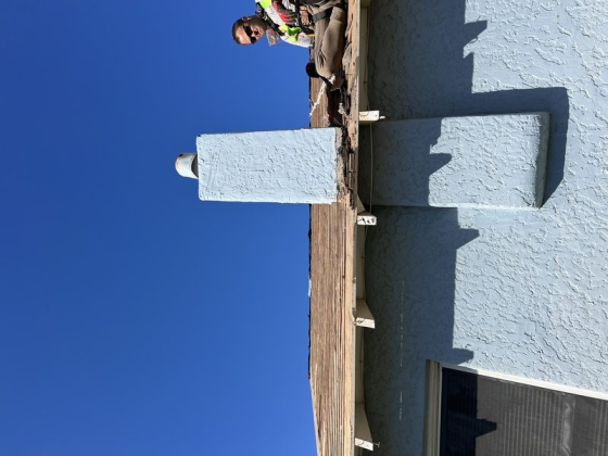 Worker repairing chimney at rooftop edge of house