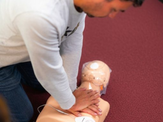 Individual performing chest compressions on a CPR dummy