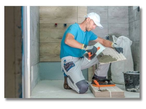 Worker applying mortar to tiles in a bathroom renovation