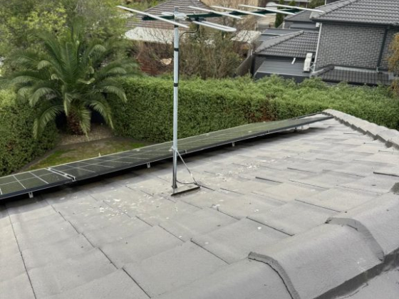 Antenna and solar panel on a house roof.