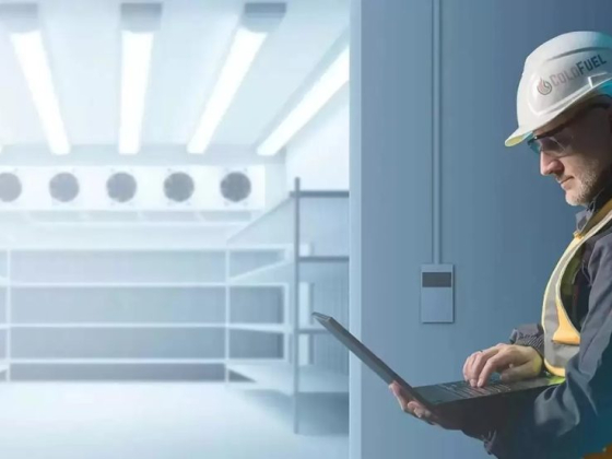 Person in hard hat using a laptop inside a storage facility
