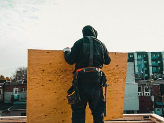 Construction worker positioning wood panel on rooftop