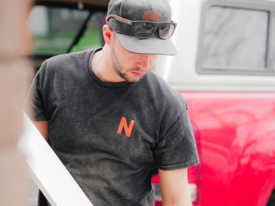 Worker holding a plank, standing near a saw