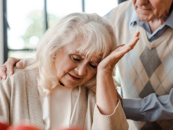 An elderly woman being consoled by an older man