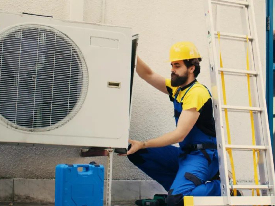 Worker in uniform adjusting air conditioning unit