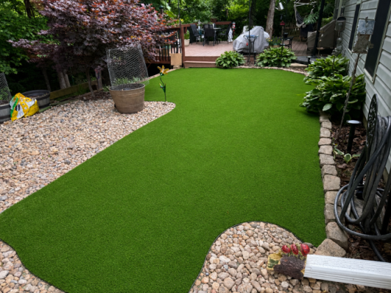 A neat yard with artificial grass, pebbles, and a patio
