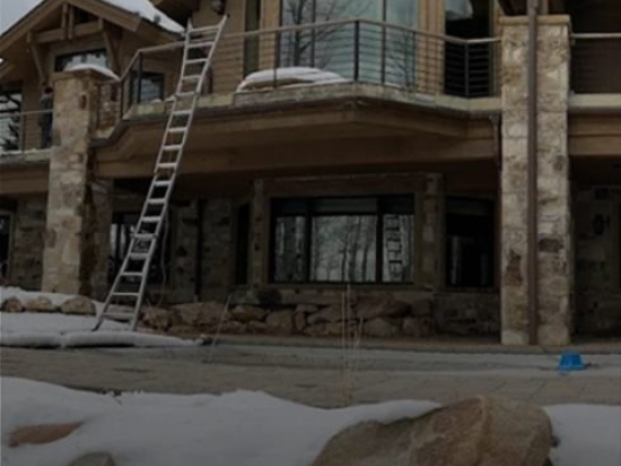Ladder leaning on large stone house in snowy setting