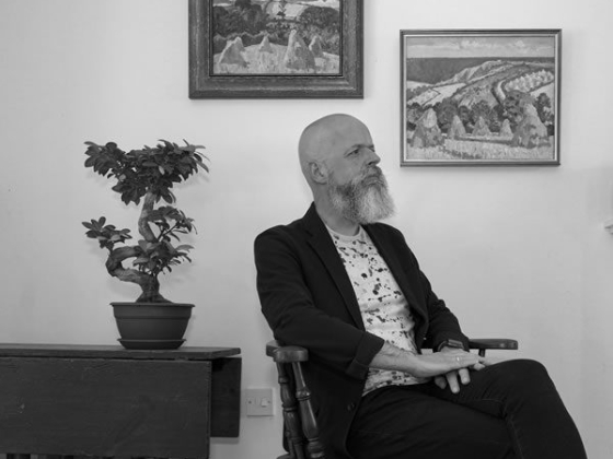 Man sitting near plant and paintings on wall