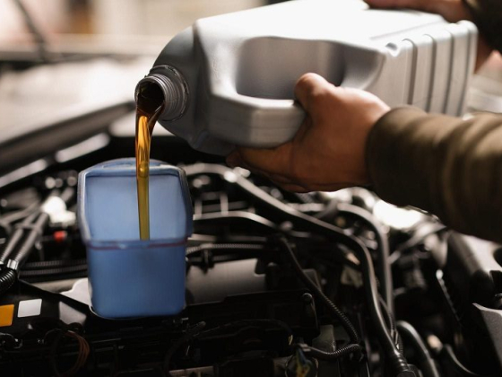 Person fills car engine with oil from a container