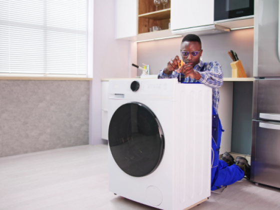 Technician kneeling to fix washing machine appliance