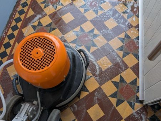 Tile floor being cleaned with a scrubbing machine