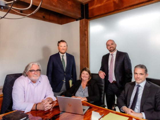 Five business people smiling in a boardroom setting