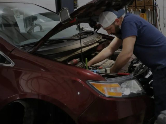 A mechanic repairs a car engine inside a garage