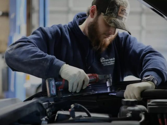 Mechanic uses a power tool under the hood of a car.