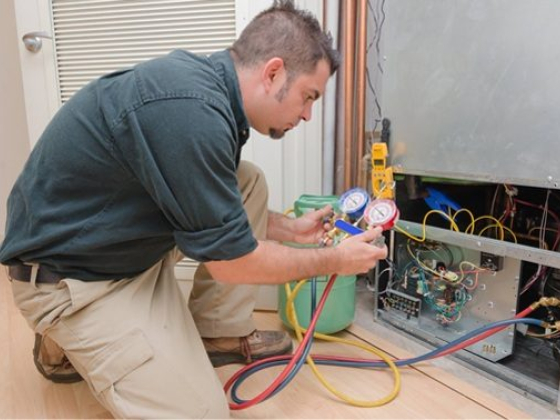 A HVAC technician performs maintenance on a unit.