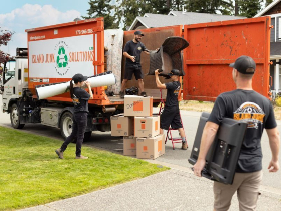 Team efficiently handling and loading discarded items outside a house