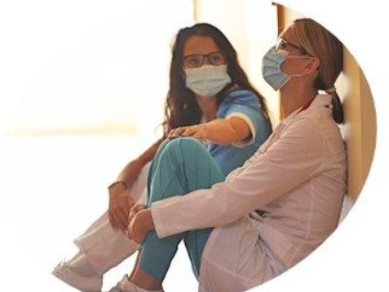 Healthcare professionals in masks resting at hospital corridor