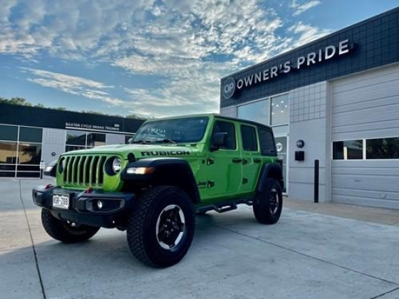 A bright green Jeep Rubicon in front of a shop
