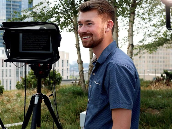 Smiling man beside teleprompter setup outside