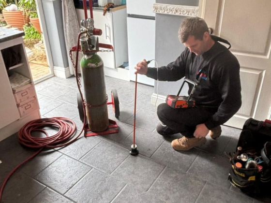 A plumber working with a gas cylinder and tools indoors