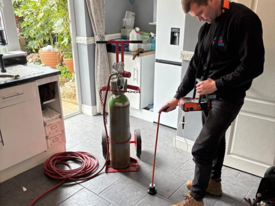 Man checking for gas leaks with equipment indoors