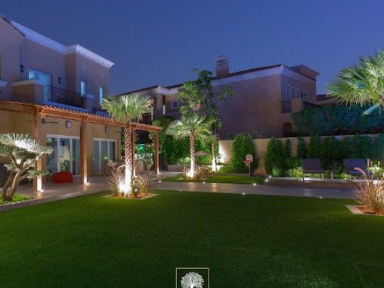 A luxurious, well-lit villa with landscaped garden in the evening
