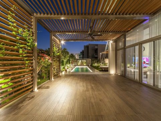 Modern patio with pergola and pool view at night
