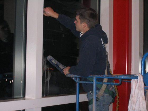 A person cleans a tall building's window at night