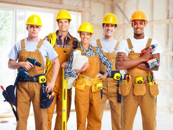 Team of five construction workers posing in a building site